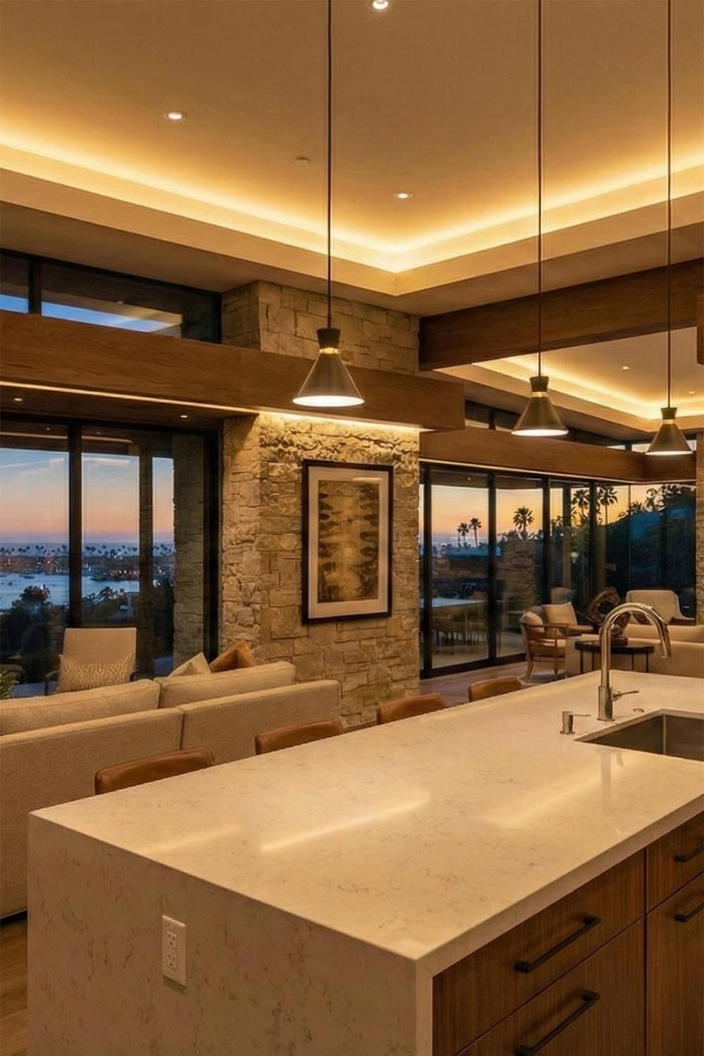 Modern kitchen and living area with warm cove lighting and sunset views