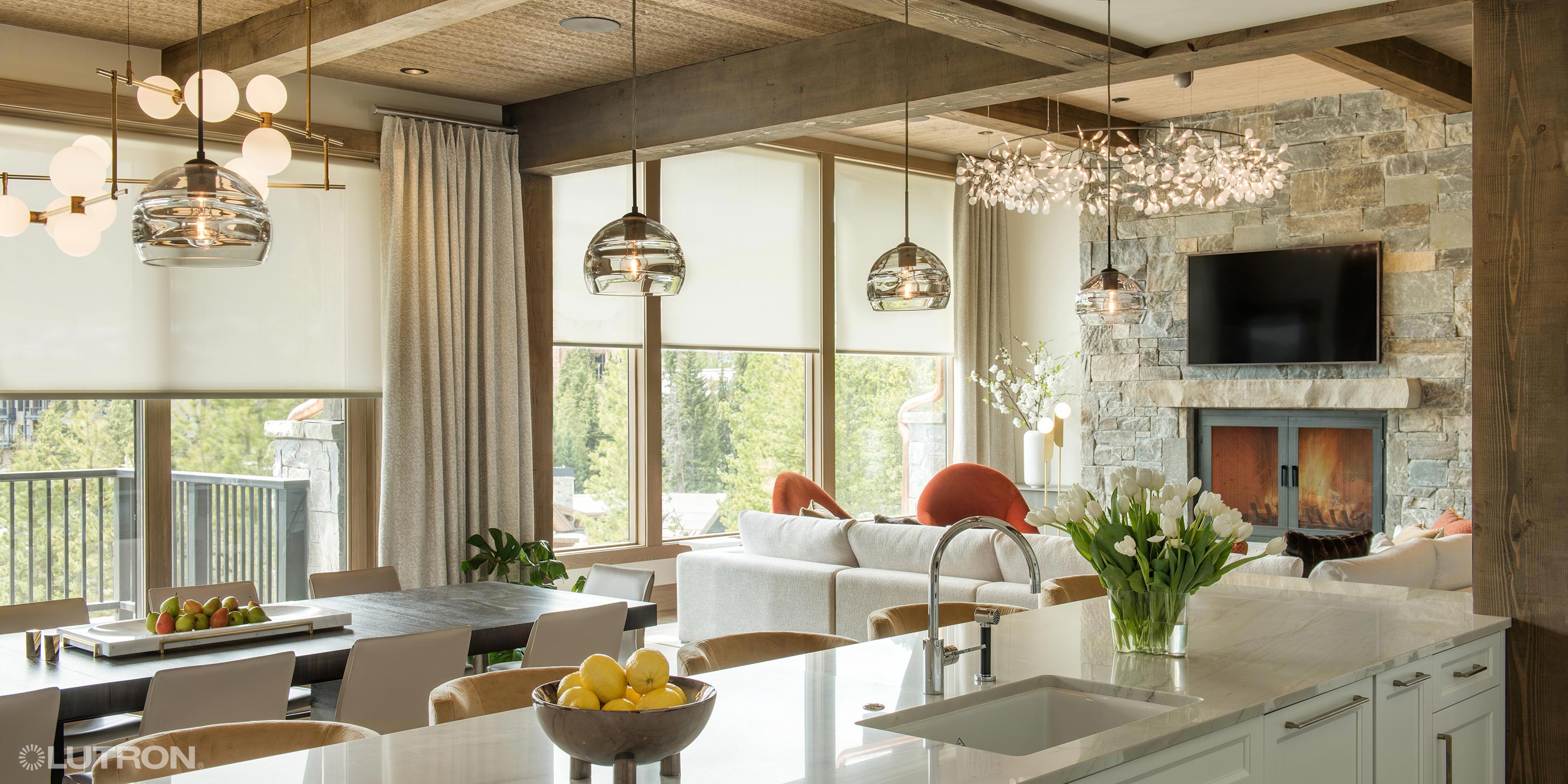 Open-concept kitchen and living space with pendant lighting and automated shades