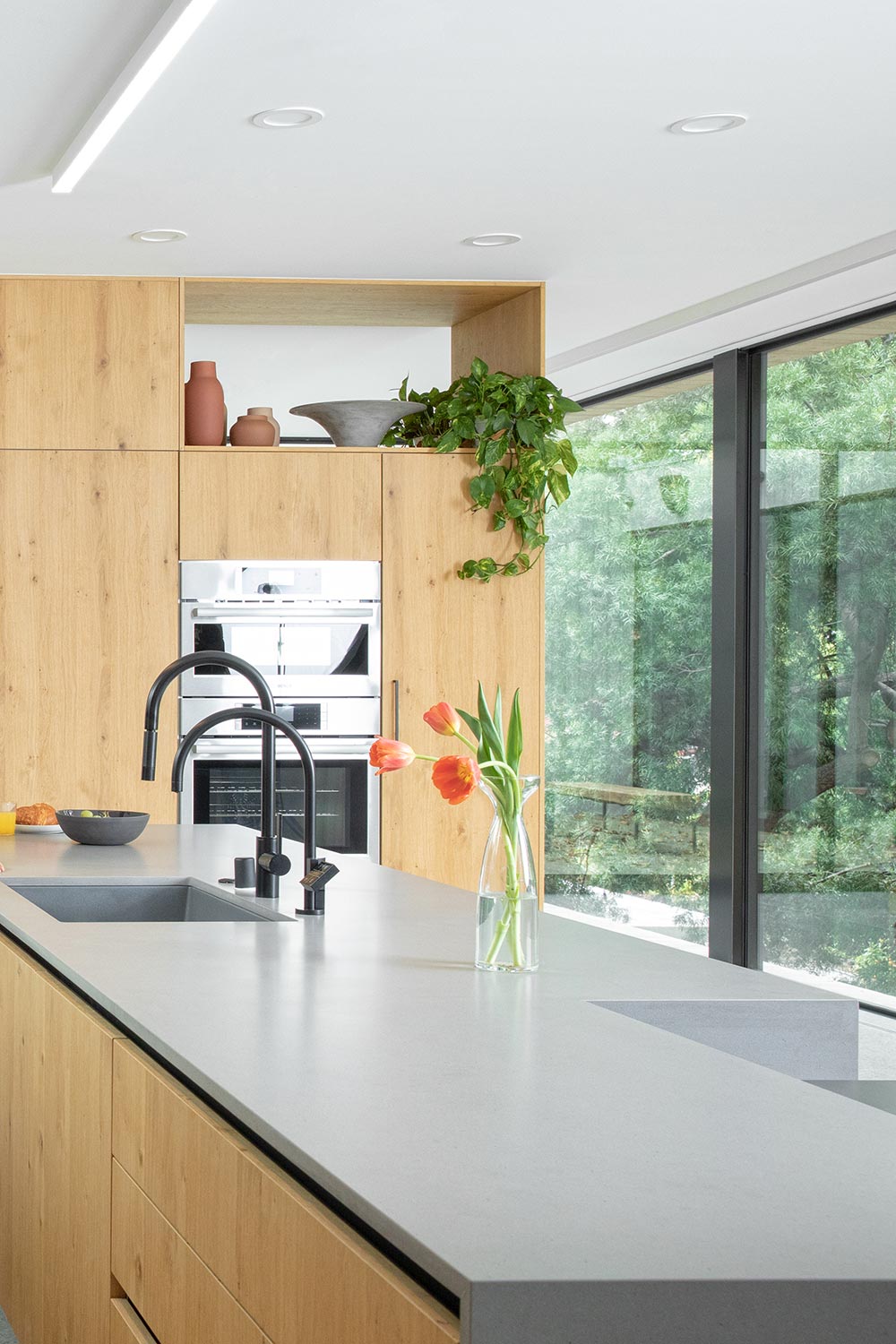 Modern kitchen island with dark faucets and orange tulips